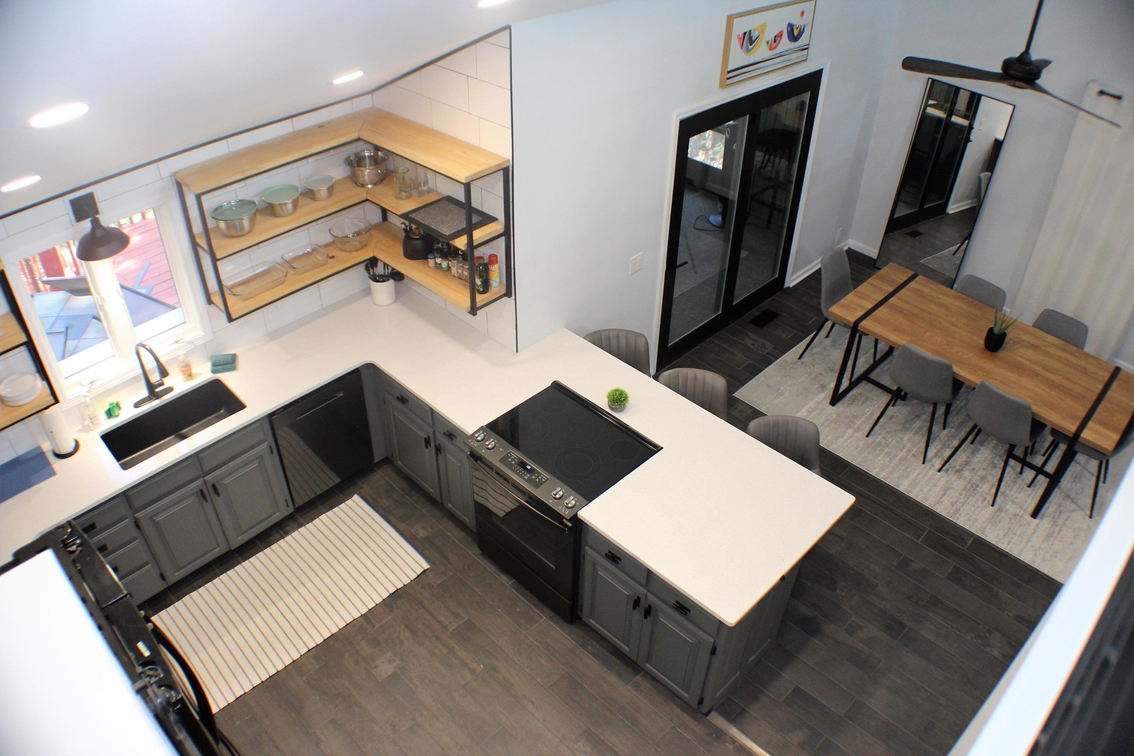Een moderne keuken met een inbouwoven, een eethoek met een houten tafel en stoelen, en een grote spiegel aan de muur.