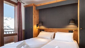 A hotel room with two beds, wooden headboard, and a view of snow-capped mountains.