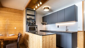Una cocina compacta con una isla de madera, electrodomésticos integrados y muebles grises.