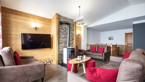 Ein modernes Wohnzimmer mit Fernseher, Holzwänden, einem Kamin und roten Kissen.