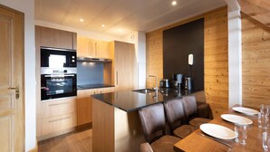 Eine moderne Küche mit Holzschränken, einem eingebauten Ofen und einem Essbereich mit Holztisch und Stühlen.