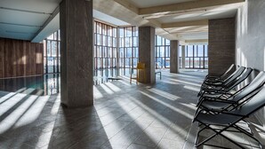 Amplio espacio interior con ventanas grandes, una piscina y una fila de sillas.