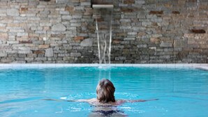 Una persona nadando en una piscina con un muro de piedra al fondo.