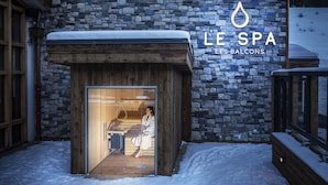 L’entrée d’un spa, avec une façade en pierre et des éléments en bois, notamment une porte en bois et un banc à l’extérieur.
