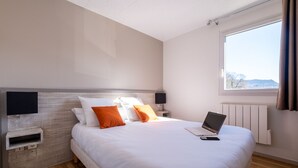 Una habitación de hotel moderna con una cama grande, una computadora portátil y vistas al exterior.