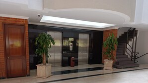 A lobby with a reception desk, two elevators, and a staircase.