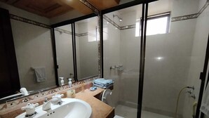 A bathroom with a large mirror, a sink, a toilet, and a shower area.