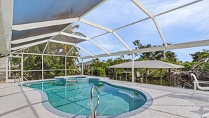 Ein überdachter Pool mit klarem, blauem Wasser, umgeben von einer gepflasterten Liegefläche und einer weißen Markise.