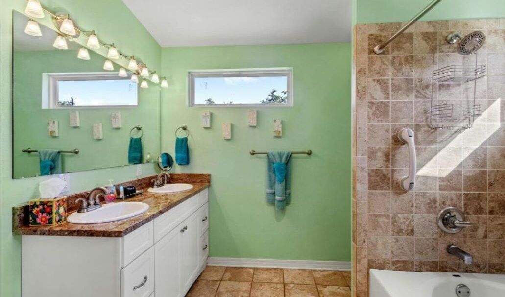 A bathroom with two sinks, a shower, and a window.