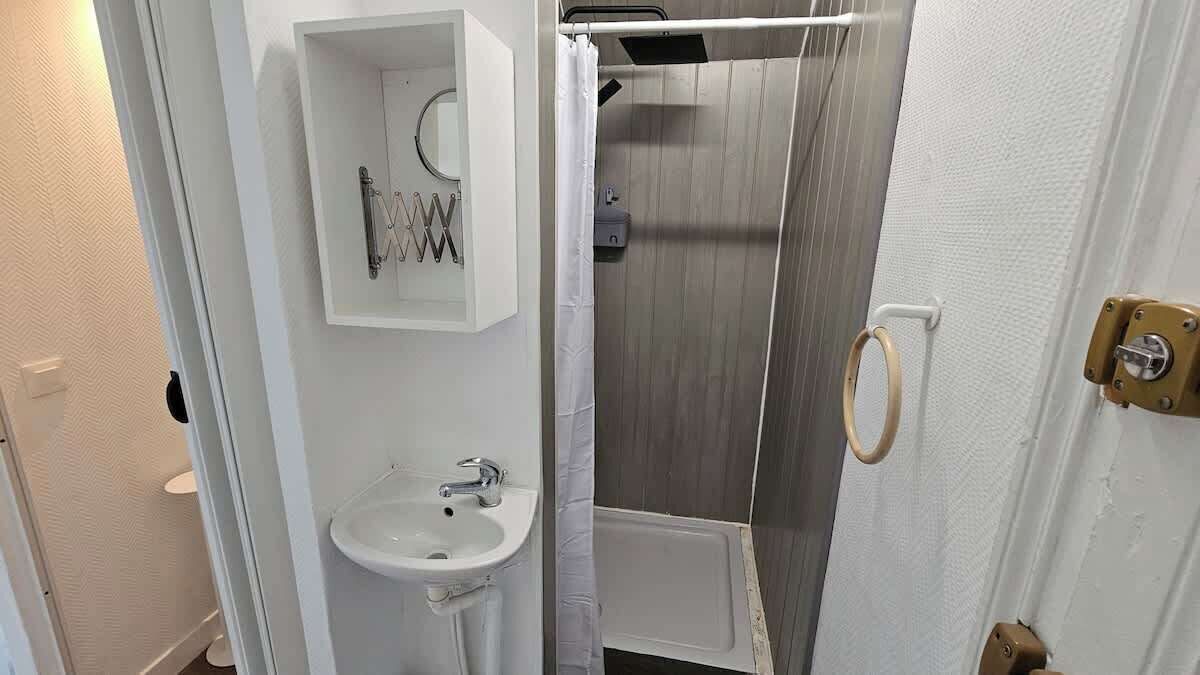 Une salle de bain avec un lavabo blanc, un miroir et un espace douche.
