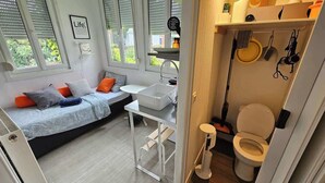 A compact room with a bed, a small table, a sink, and a toilet. - Les Glycines - studio 9m2 cosy et reposant 1p (Arras)