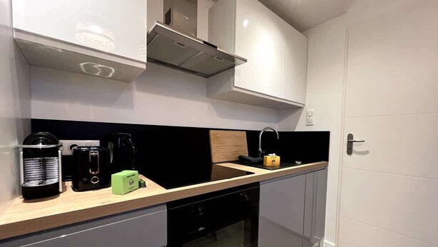 Una cucina moderna con mobili bianchi, un piano di lavoro nero e un forno integrato.