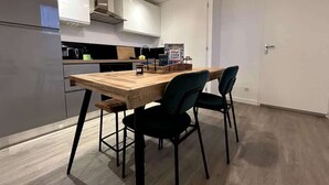 Una cucina moderna con un tavolo in legno e sedie nere, una macchina da caffè e un lampadario.