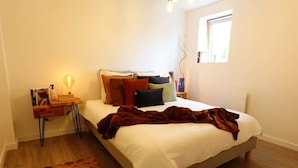 Una camera da letto con un letto, un comodino con una lampada e una finestra.