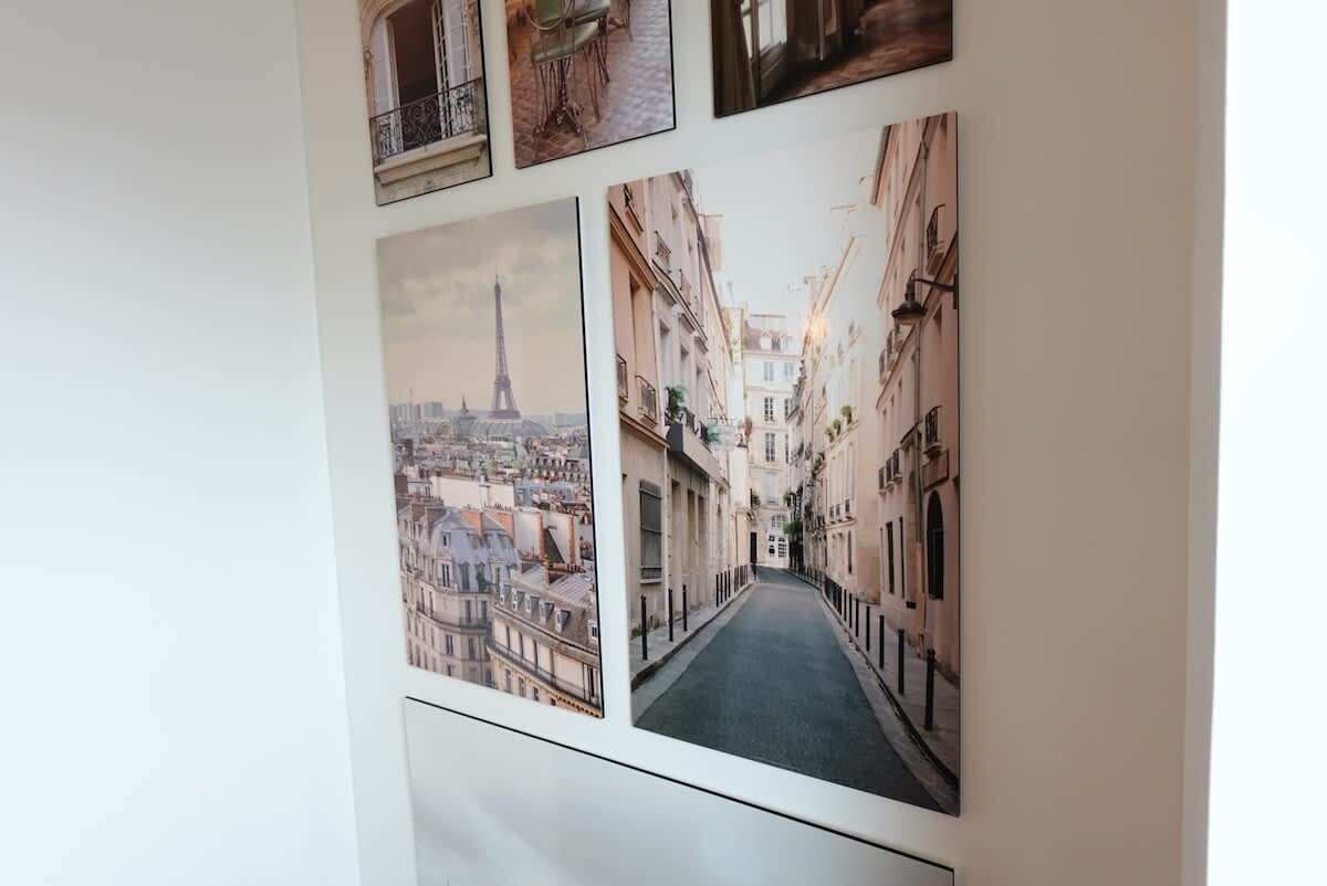 A wall with three framed photographs depicting urban scenes, including a street with buildings and a view of the Eiffel Tower.