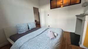 A bedroom with a bed, pillows, and a bedside table. - L'Échappée Boisée Arrageoise • 2 ch • Gare (Arras)