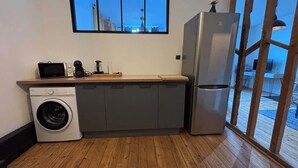 A compact kitchen with a washing machine, a microwave, and a refrigerator. - L'Échappée Boisée Arrageoise • 2 ch • Gare (Arras)