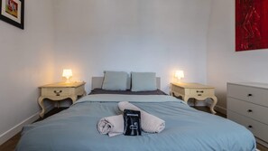 A neatly made bed with a welcome bag, two bedside tables with lamps, and a dresser. - Villa Arrageoise • Parking • hypercentre • 3e étage (Arras)