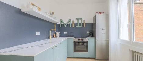 A modern kitchen with light blue cabinets, a stainless steel oven, and a refrigerator.