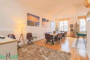 A spacious dining area with a wooden table and chairs, a large rug, and artwork on the walls.