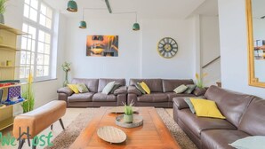 Ein modernes Wohnzimmer mit einem braunen Ledersofa, einem Holztisch und einer grünen Pendelleuchte.