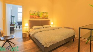 Ein Schlafzimmer mit Bett, Nachttischlampen, einem Gemälde und einem Sessel.
