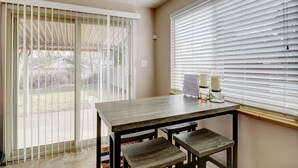 A dining area with a table and benches, a ceiling fan, and a view through a sliding glass door.