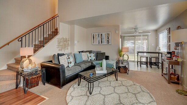A living room with a staircase, a sofa, a coffee table, and a dining area.