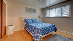 A bedroom with a bed, a window with blinds, a wall-mounted light, and a floor lamp.