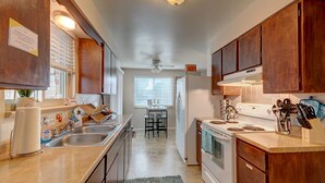 A kitchen with wooden cabinets, a sink, a stove, and a ceiling fan.