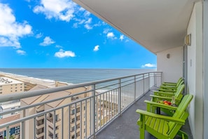 Ein Balkon mit Blick auf das Meer, grünen Stühlen und einem Geländer.