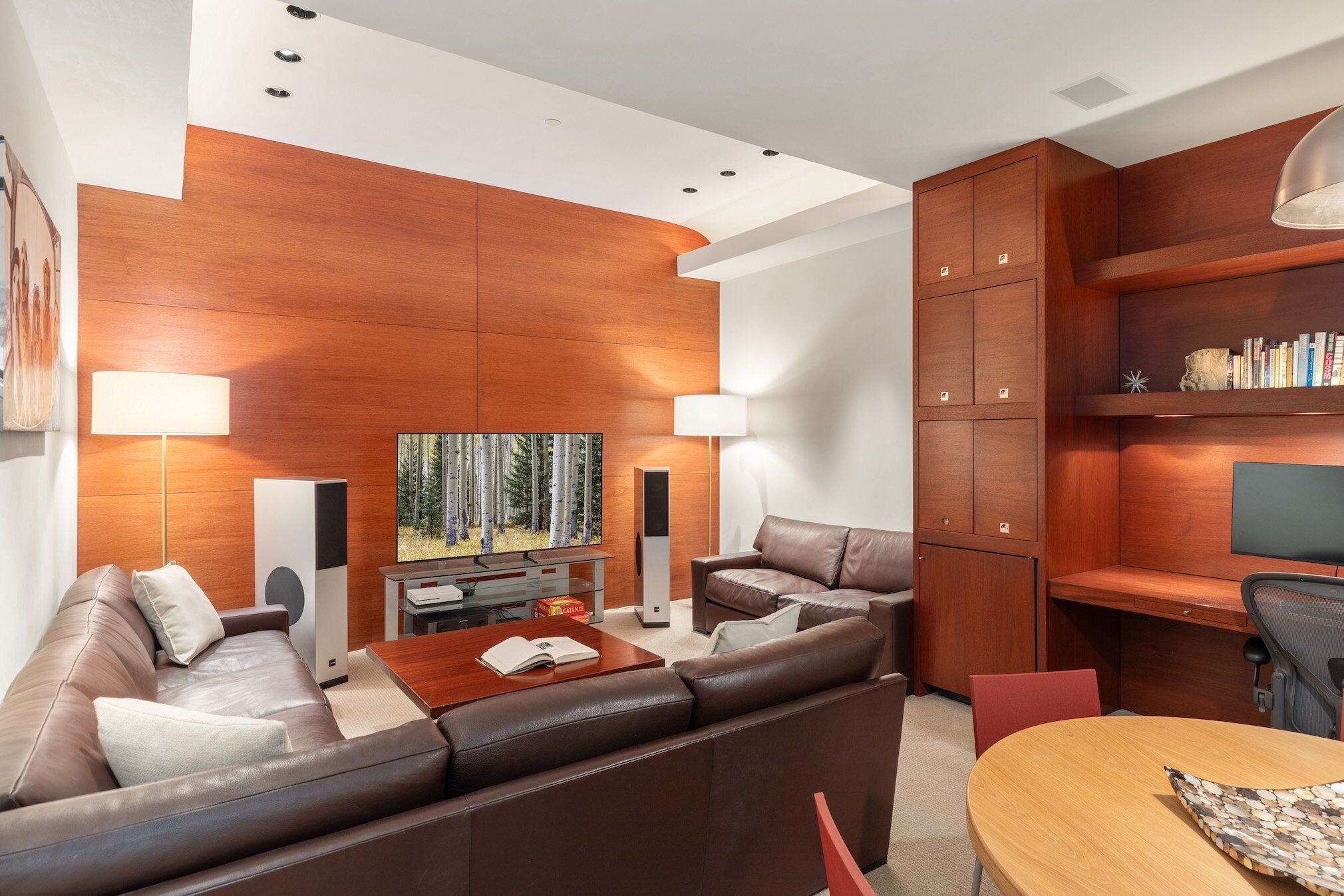Un salon moderne avec un canapé en cuir marron, un meuble en bois et un téléviseur.