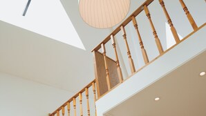 Un interior moderno con una cafetera sobre una mesa de madera, una escalera con barandilla de madera y un tragaluz.