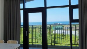 Una habitación moderna con un gran ventanal corredero que da a un balcón con vistas al mar.