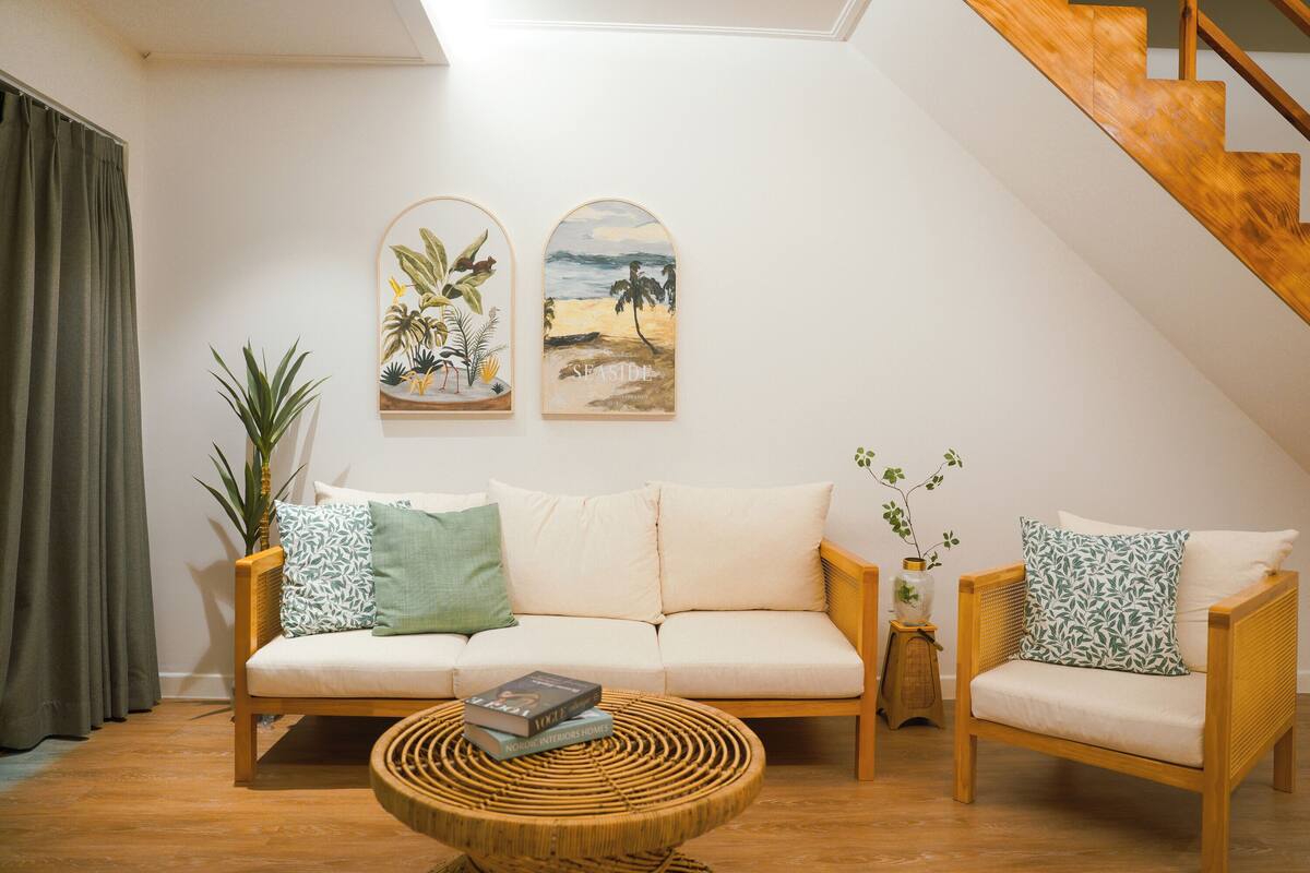 Een woonkamer met een bank, twee fauteuils, een salontafel en twee aan de muur bevestigde schilderijen.