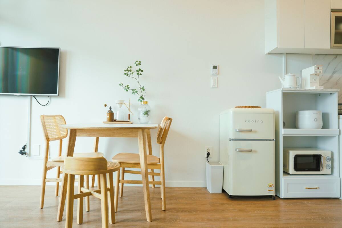 Een moderne keuken met een eettafel, stoelen, een witte koelkast en een magnetron.