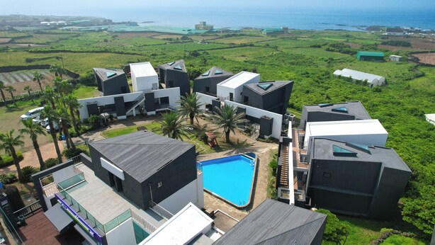 Un moderno resort con piscina, palmeras y vistas al océano.