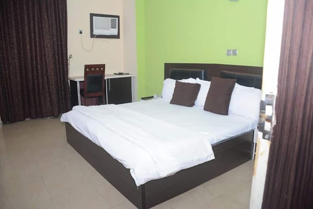 A hotel room with a large bed, a desk, and a chair.