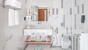 A modern bathroom with a marble floor, a white sink, a glass shower enclosure, and a toilet. - Standard Room Near Maktoum Airport By E R (Dubai)