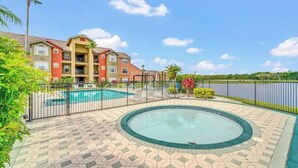 A hotel with a swimming pool, a hot tub, and a view of a lake. - Luxe King Suite Bliss Getaway Condo Near Disney  (Kissimmee)