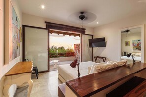 Een hotelkamer met balkon, bed, bureau, stoel, televisie en raam met uitzicht op de omgeving.