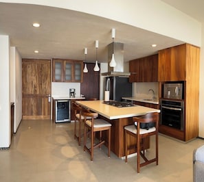 A modern kitchen with wooden cabinets, a central island, and stainless steel appliances.