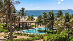 A resort with a pool, palm trees, and a view of the ocean.