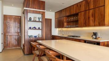 A modern kitchen with wooden cabinetry, a central island with bar stools, and built-in shelves with decorative items.