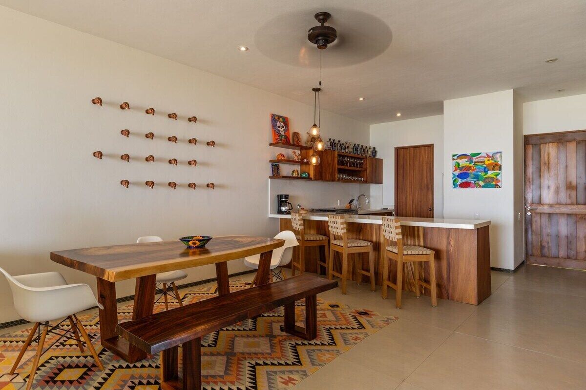 A modern kitchen with wooden cabinets, a central island, and pendant lighting.