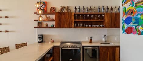 A modern kitchen with wooden cabinets, a built-in oven, a dishwasher, and a dining area with a long table.