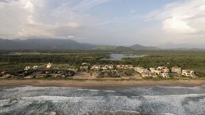 A coastal resort with beachfront villas, a beach, and a mountainous backdrop. - 2BR Beachfront Villa + Pool, Style & Sea Views (Zihuatanejo)