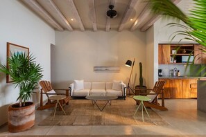 A living room with a sofa, two chairs, a coffee table, a floor lamp, and a potted plant. - 2BR Beachfront Villa + Pool, Style & Sea Views (Zihuatanejo)