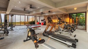 A gym with various exercise equipment, large windows, and a stone wall. - 2BR Beachfront Villa + Pool, Style & Sea Views (Zihuatanejo)