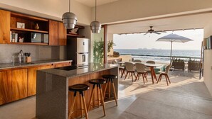 A modern kitchen with a large island, bar stools, and a view of the ocean. - 2BR Beachfront Villa + Pool, Style & Sea Views (Zihuatanejo)